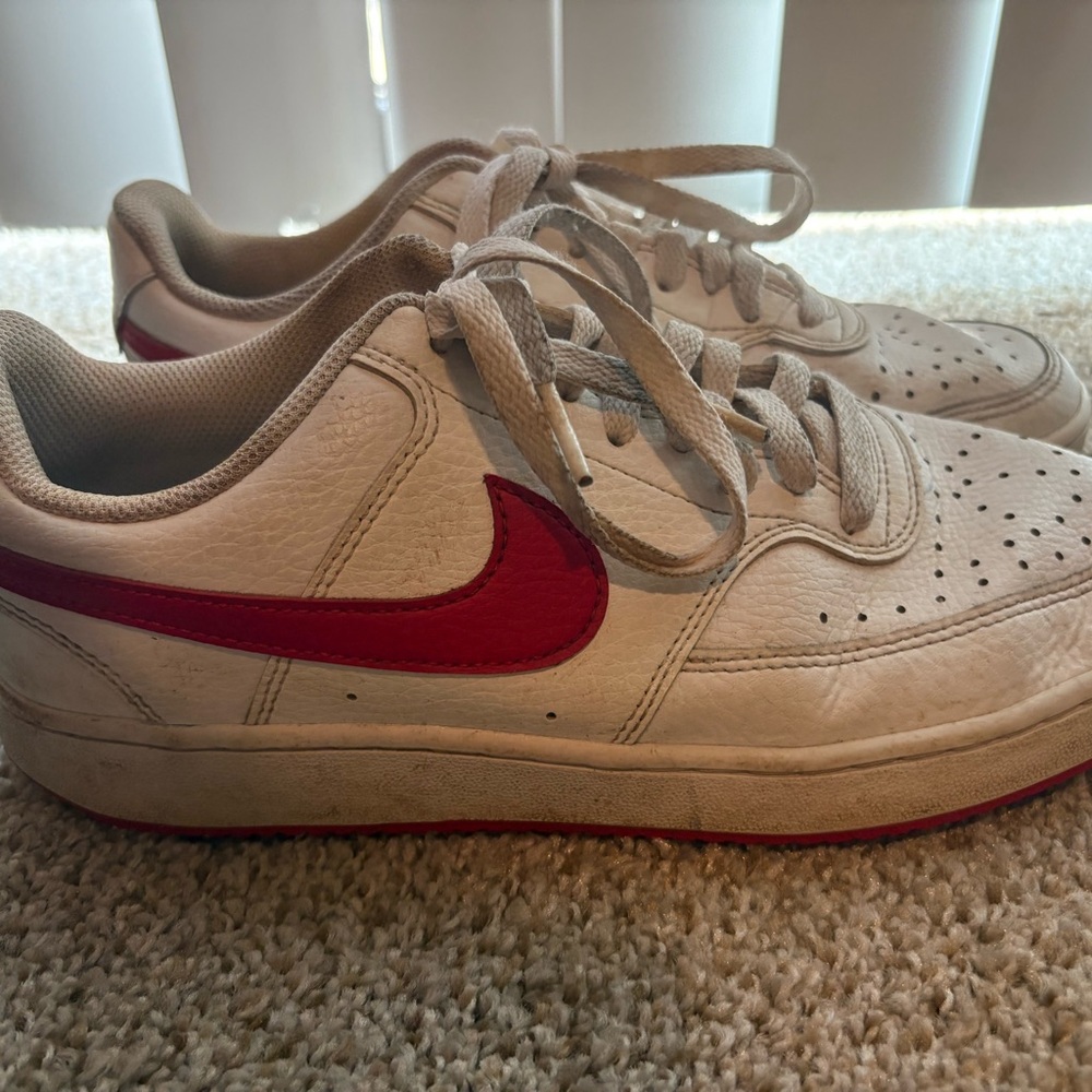 Slightly worn white Nikes with red swoosh and red bottom